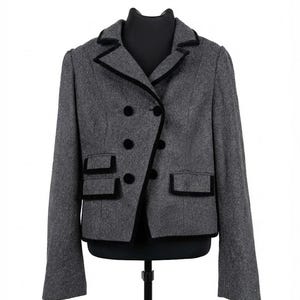 May include: A charcoal grey wool-blend blazer featuring a double-breasted front with black velvet buttons and matching black velvet trim along the notched lapels, hem, and two front flap pockets. The jacket has long sleeves and a structured fit.