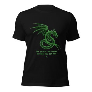 May include: A black short-sleeved t-shirt featuring a green dragon graphic composed of digital code. Below the dragon, the text reads: The quieter you become, the more you can hear. A command prompt cursor symbol is positioned at the bottom of the text.