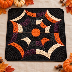 May include: A square quilted table mat featuring a central orange circle surrounded by a radiating spiderweb pattern. The design uses black, orange, and cream fabric segments with intricate stitching, creating a geometric, seasonal aesthetic.