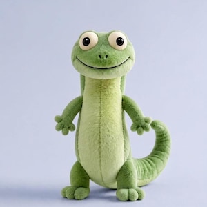 May include: A plush lizard toy featuring a soft, light green textured body with a lighter green underbelly. The creature has large, round, dark-pupiled eyes, a wide smiling mouth, four-toed feet, and a long, curved tail extending to the right.