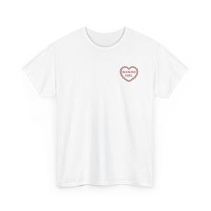 Może przedstawiać: Biały t-shirt z krótkim rękawem z małą grafiką na lewej piersi. Grafika przedstawia czerwone serce z ozdobną, falistą obwódką, wewnątrz którego znajduje się napis "BOOKISH GIRL" wykonany prostą, czytelną czcionką.