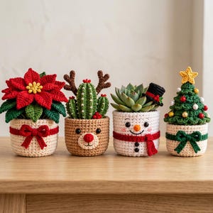 Könnte beinhalten: Vier gehäkelte Pflanzenüberzüge mit weihnachtlichen Motiven: ein cremefarbener Überzug mit roter Schleife, ein beigefarbener Rentier-Überzug mit Geweih, ein weißer Schneemann-Überzug mit rotem Schal und Zylinder sowie ein cremefarbener mit grüner Schleife.