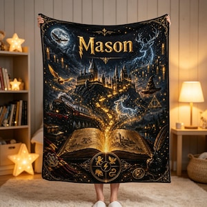 May include: A black fleece blanket featuring the name Mason in gold lettering. The design includes a glowing open book, a steam train, a castle, a stag, a bird, a wizard hat, and floating candles. The artwork is rendered in shades of gold, blue, and black.