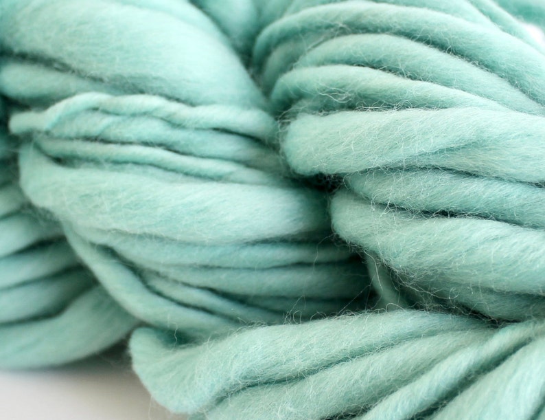 May include: A close-up of a skein of soft, light blue yarn. The yarn is made of wool and is perfect for knitting or crocheting.