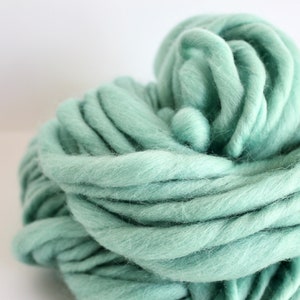 May include: A large skein of soft, light green yarn. The yarn is made of wool and is perfect for knitting or crocheting.