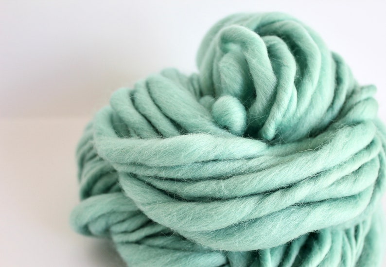May include: A large skein of soft, light green yarn. The yarn is made of wool and is perfect for knitting or crocheting.