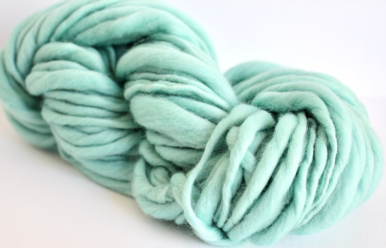 May include: A skein of light blue yarn, made of soft, fluffy fibers. The yarn is thick and chunky, perfect for knitting or crocheting.