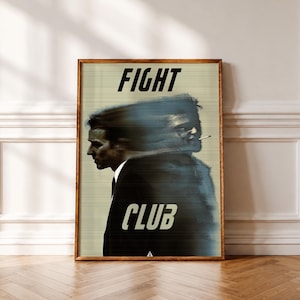 May include: A framed rectangular poster featuring a motion-blurred graphic of two figures in dark suits, one with a cigarette. The text FIGHT is printed in black at the top, and the text CLUB is printed in white at the bottom on a beige background.