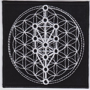 May include: A black fabric patch with a white embroidered design of a flower of life and a tree of life. The design is intricate and detailed.