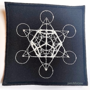 Puede incluir: Parche de tela negro con un diseño geométrico bordado en blanco. El diseño presenta una estrella, círculos y líneas. El parche tiene un borde cosido blanco y el texto "patchforyou" en la esquina inferior derecha.