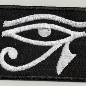 Könnte beinhalten: Schwarzer Stoff-Patch mit einem weißen gestickten Horus-Auge.