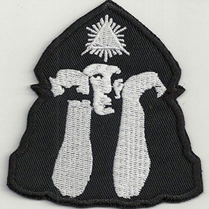 Könnte beinhalten: Schwarzer gestickter Aufnäher mit einem weißen Design aus zwei Händen, die ein Dreieck mit einem Stern darin halten. Der Aufnäher hat einen gezackten Rand.