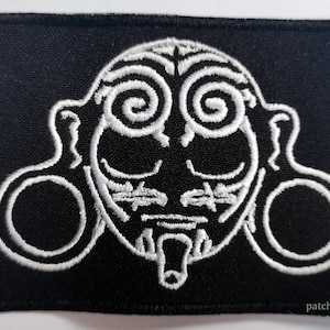 May include: White embroidered patch on a black background featuring a stylized face with large ear gauges and swirling designs around the eyes. The text "patchforyou" is visible in the bottom right corner.