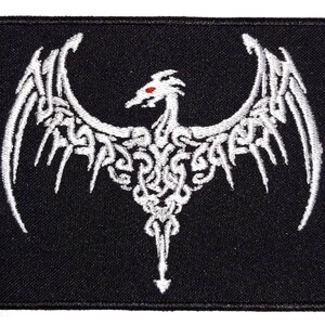 May include: White embroidered patch with a detailed design of a dragon with wings spread wide. The dragon has a red eye and is on a black background.