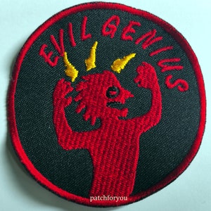 Op de afbeelding: Een geborduurde zwarte en rode patch met de tekst "EVIL GENIUS" in gele letters. Een rode cartoon-duivel met gele hoorns bevindt zich in het midden van de patch.