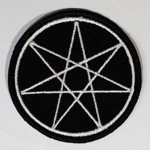 Può includere: Una toppa ricamata in bianco e nero con una stella bianca a sette punte al centro.