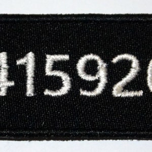 Puede incluir: Parche de tela negro con texto bordado en blanco que dice "3.14159265..."