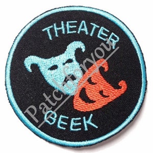 Puede incluir: Un parche bordado circular negro y azul con el texto "THEATER SEEK" y dos máscaras estilizadas, una azul y otra roja.