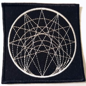 Può includere: Toppa ricamata nera con un cerchio bianco che contiene un motivo geometrico di linee che si intersecano.