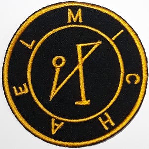 Op de afbeelding: Een geborduurde zwarte en gouden patch met een zegel en de letters "M", "I", "C", "H", "A", "E", "L" rond de rand.