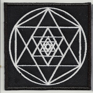 May include: A black fabric patch with a white embroidered geometric design. The design features a circle with a series of overlapping triangles and lines.