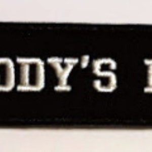 May include: Black embroidered patch with white lettering that reads "DADDY'S BOY".