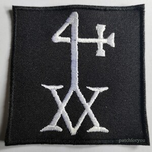 Puede incluir: Parche blanco bordado sobre fondo negro con el símbolo "4" y "XX" debajo.