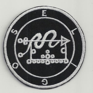 Könnte beinhalten: Ein gestickter schwarzer und weißer Aufnäher mit einem Kreisdesign. Der Kreis enthält ein Symbol mit einer Schlange und einem Pfeil. Die Buchstaben "E", "S", "O" und "G" befinden sich um den Kreis herum.