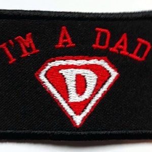 May include: Black embroidered patch with red and white lettering that reads "I'm a Dad" with a red diamond shape with a white "D" inside.