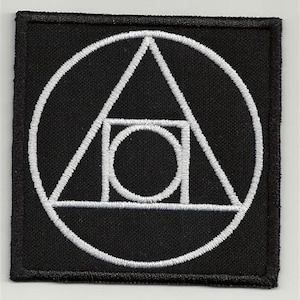 Op de afbeelding: Een zwarte stoffen patch met een wit geborduurd ontwerp. Het ontwerp bevat een cirkel, een driehoek, een vierkant en een kleinere cirkel binnen het vierkant.