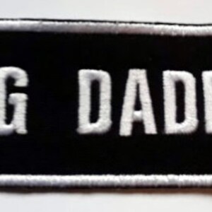 May include: White embroidered patch with a black background and the text "BIG DADDY" in white.