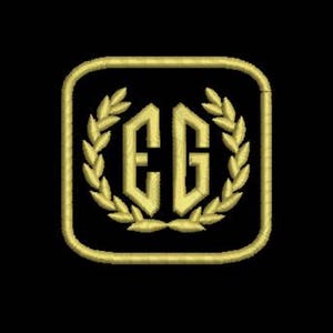 Pu&ograve; includere: Monogramma ricamato in oro con le lettere "EG" all'interno di una cornice quadrata con una corona di alloro intorno alle lettere.