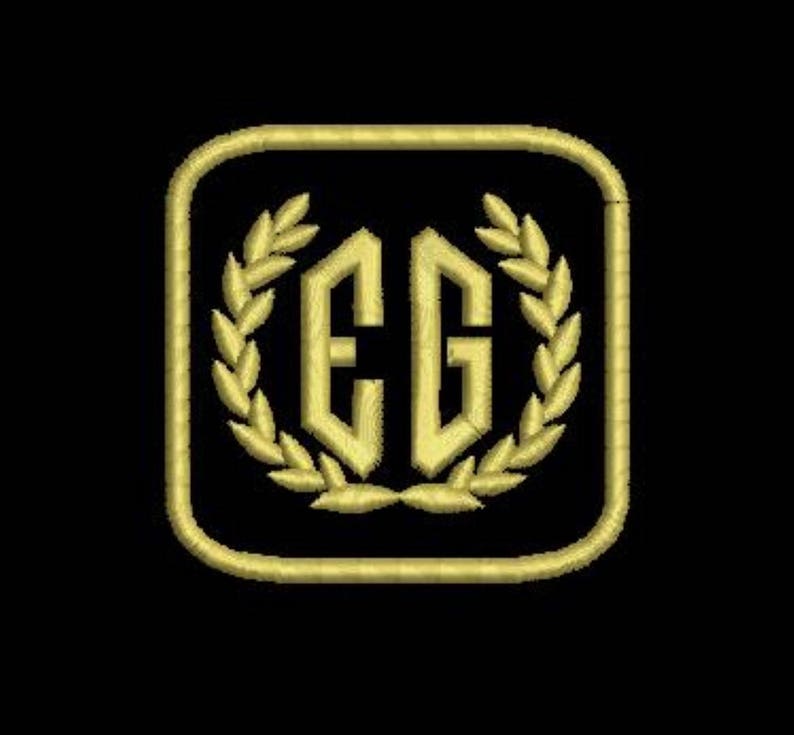 Pu&ograve; includere: Monogramma ricamato in oro con le lettere "EG" all'interno di una cornice quadrata con una corona di alloro intorno alle lettere.