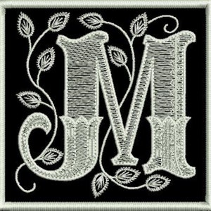 Può includere: Una lettera M ricamata in bianco con un motivo floreale decorativo su uno sfondo nero.