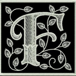 Op de afbeelding: Witte geborduurde letter F met een decoratief rank- en bladontwerp op een zwarte achtergrond.