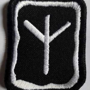 Könnte beinhalten: Weiß gesticktes Symbol auf einem schwarzen Patch. Das Symbol ist ein stilisierter Baum mit drei Ästen. Der Patch hat einen weißen Rand und ist rechteckig.