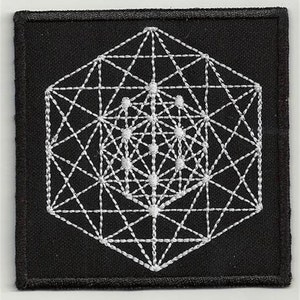 May include: A black fabric patch with a white embroidered geometric design. The design is a complex, multi-layered pattern of intersecting lines and dots, resembling a mandala or sacred geometry.