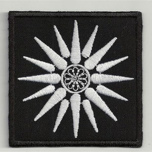 Puede incluir: Parche bordado blanco con una estrella de 16 puntas sobre un fondo negro.