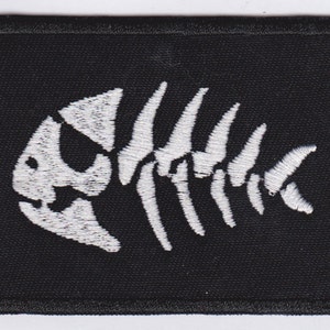 May include: White embroidered fish skeleton design on a black fabric patch.