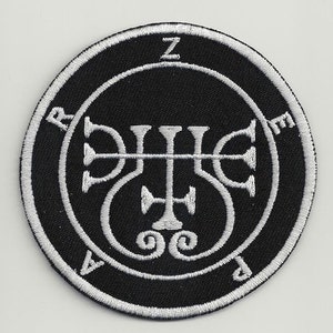 Pode incluir: Um remendo bordado preto e branco com um selo no centro. O selo é cercado por um círculo com as letras "Z", "P", "E" e "A" ao redor.
