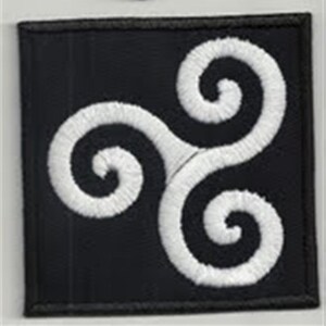Pode incluir: Um remendo de tecido preto com um design de espiral tripla bordado em branco. O design é um nó celta, também conhecido como triskelion.