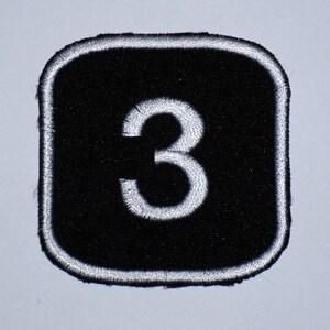 May include: Black square patch with a white number 3 embroidered on it.