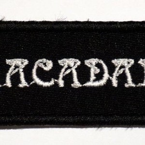 May include: Black embroidered patch with white lettering that reads "ABRACADABRA".