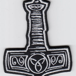 Könnte beinhalten: Schwarz-weiß gestickter Aufnäher mit einem Hammer mit dekorativem Design. Der Hammer ist ein Symbol für Stärke und Macht.