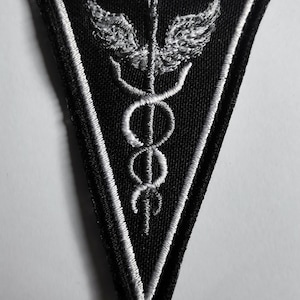 May include: Black triangular patch with a white embroidered medical symbol, a snake wrapped around a staff with wings.