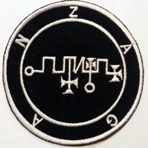 Pode incluir: Um remendo bordado preto e branco com um selo e as letras "ZAZAG" ao redor da borda.