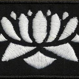 Può includere: Toppa di tessuto nero con un motivo di fiore di loto ricamato in bianco.