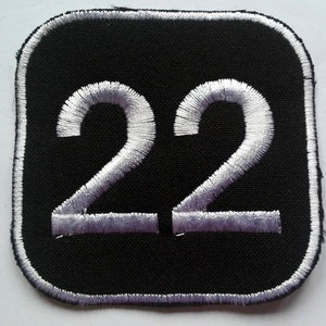 May include: A black square patch with a white embroidered number 22.