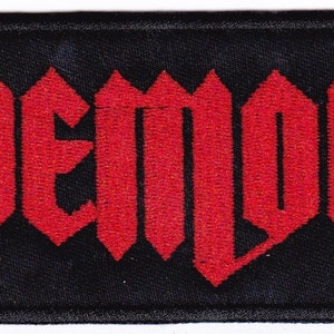 Puede incluir: Parche bordado rojo con la palabra "Demon" en una fuente gótica sobre un fondo negro.