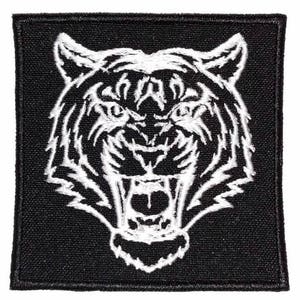 May include: White embroidered tiger head on a black fabric patch. The tiger's mouth is open and its teeth are visible.